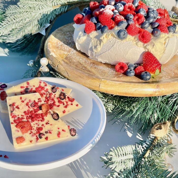 Decorative pavlova dessert with white chocolate and berries on a festive background with a white chocolate pavlova bar