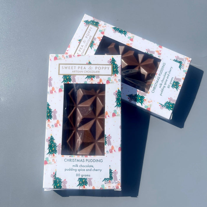 Two chocolate bars in decorative Christmas packaging on a grey surface