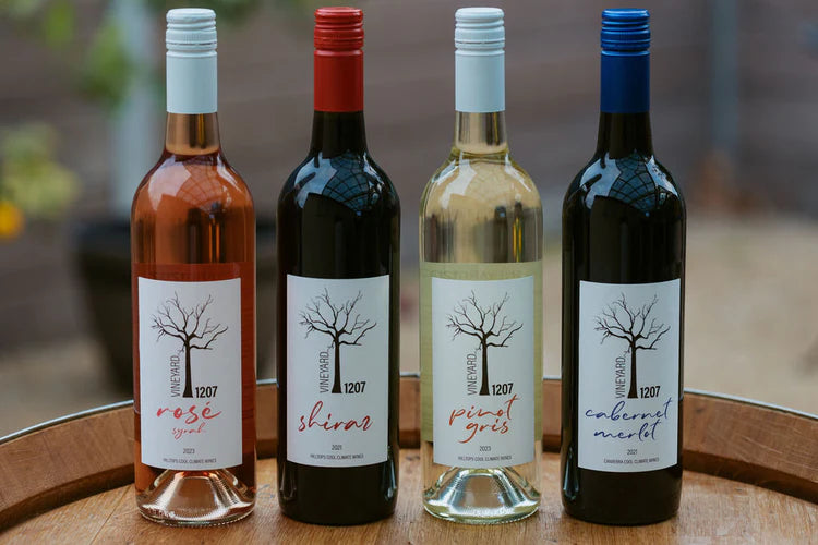 Four wine bottles with labels on a wooden surface