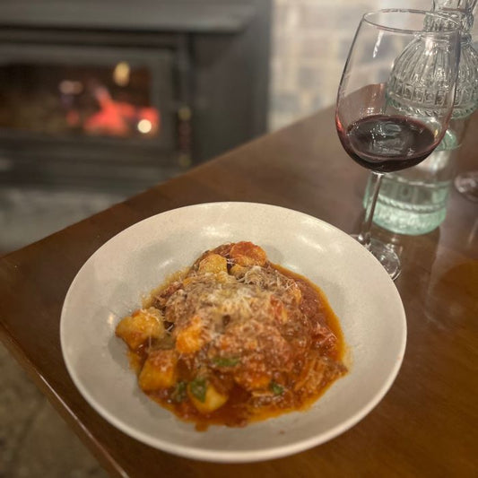 A restaurant setting with ragu, wine and a fireside background