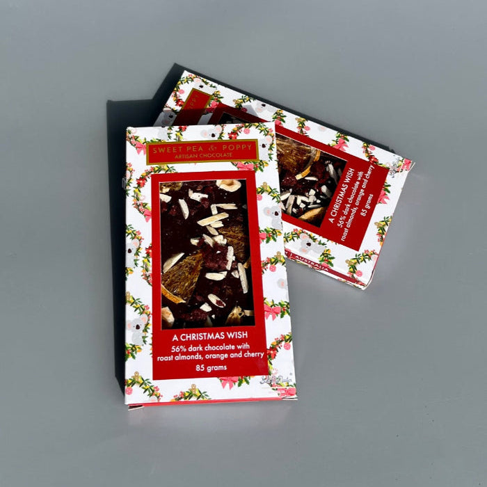 Two chocolate bars with Christmas packaging with festive designs on a grey background