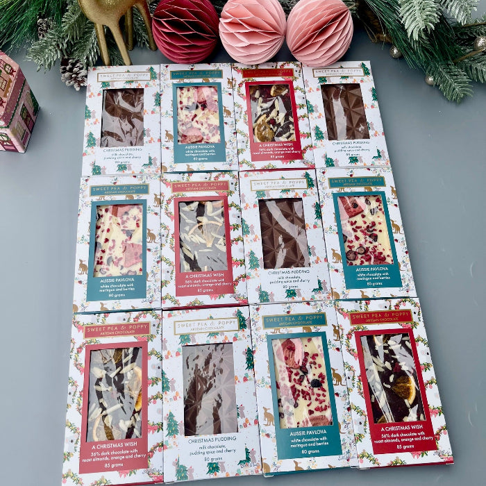 12 gift boxed chocolate bars with Christmas packaging on a grey background with festive decoration