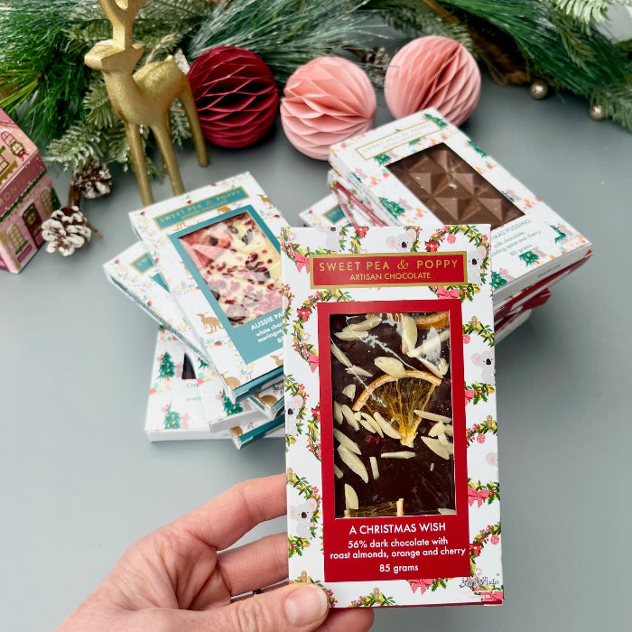 Hand holding a chocolate bar with decorative packaging against a festive background