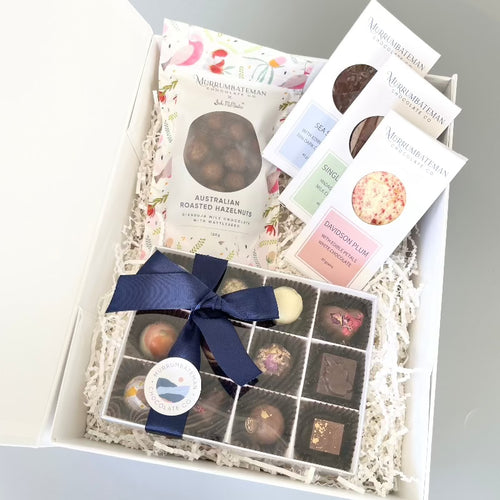 A gift hamper containing a box of 12, gift boxed chocolate truffles, three boxed chocolate bars and a packet of chocolate coated hazelnuts