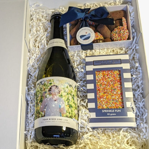 A gift box with sparklig wine, a chocolate gift box and a sprinkle chocolate bar